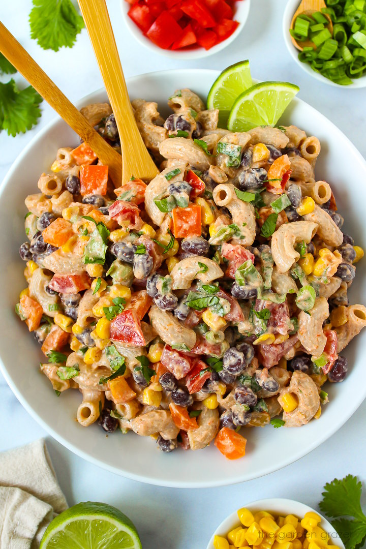 Overhead view of vegan Mexican macaroni salad in a white serving bowl with fresh lime slices