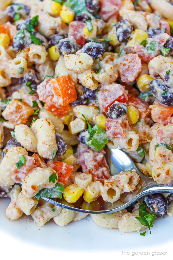 Close up view of Mexican macaroni salad with black beans and veggies on a white plate