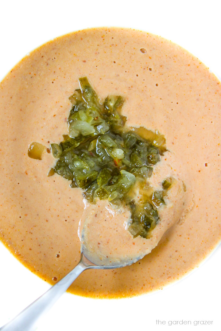 Stirring together thousand island dressing and pickle relish in a small glass bowl