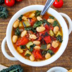 Tomato white bean soup in a white serving bowl on a wooden table