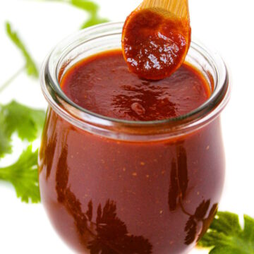 Vegan BBQ sauce in a small glass jar with wooden serving spoon