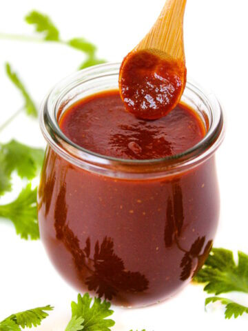 Vegan BBQ sauce in a small glass jar with wooden serving spoon