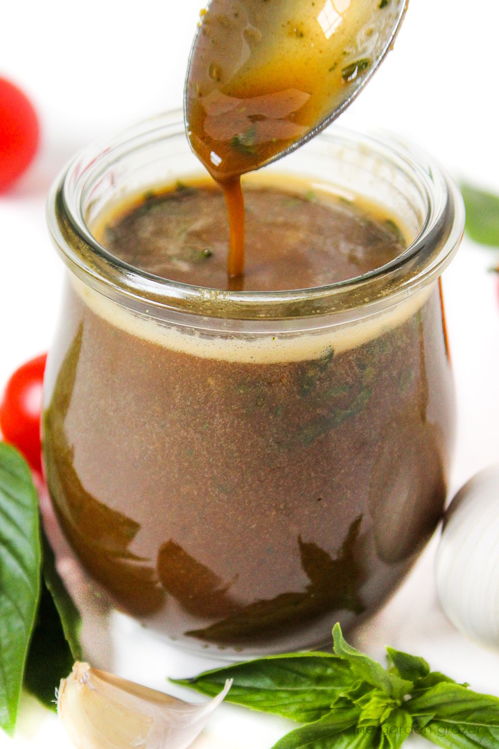 Close up view of spoon scooping out basil balsamic dressing from a glass jar