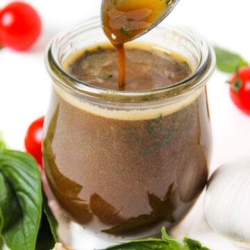 Oil-free basil balsamic dressing in a small glass jar with serving spoon