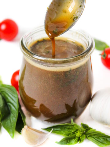 Oil-free basil balsamic dressing in a small glass jar with serving spoon