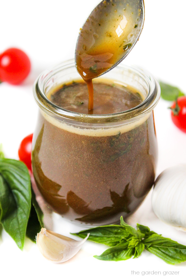 Oil-free basil balsamic dressing in a small glass jar with serving spoon