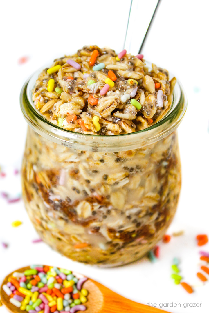 Vegan birthday cake batter overnight oats in a glass jar with serving spoon