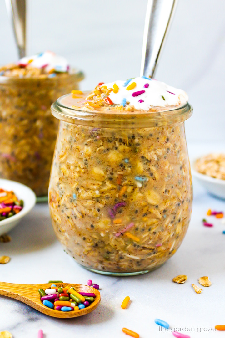 Close up view of birthday cake overnight oats in a glass serving jar with spoon