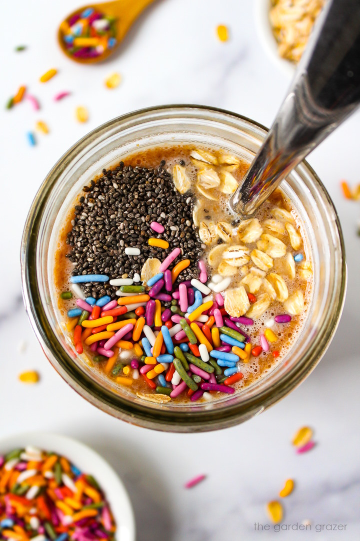 Overhead view of preparing oat mixture in a glass jar before stirring together