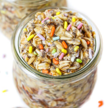 Vegan birthday cake overnight oats in a small glass jar with colored sprinkles