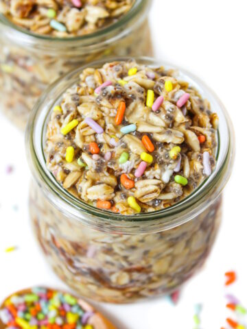Vegan birthday cake overnight oats in a small glass jar with colored sprinkles