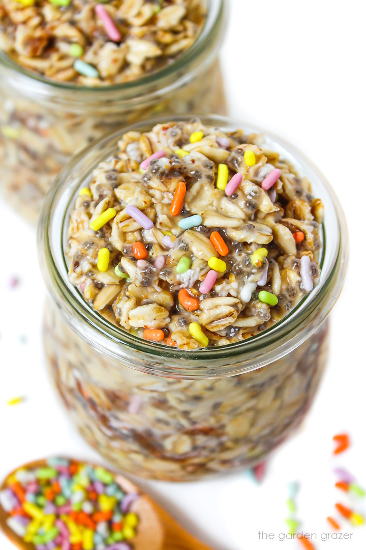 Vegan birthday cake overnight oats in a small glass jar with colored sprinkles