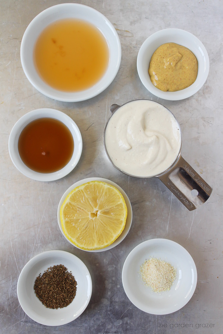 Cashew mayo, vinegar, mustard, lemon, and spice ingredients laid out on a metal tray