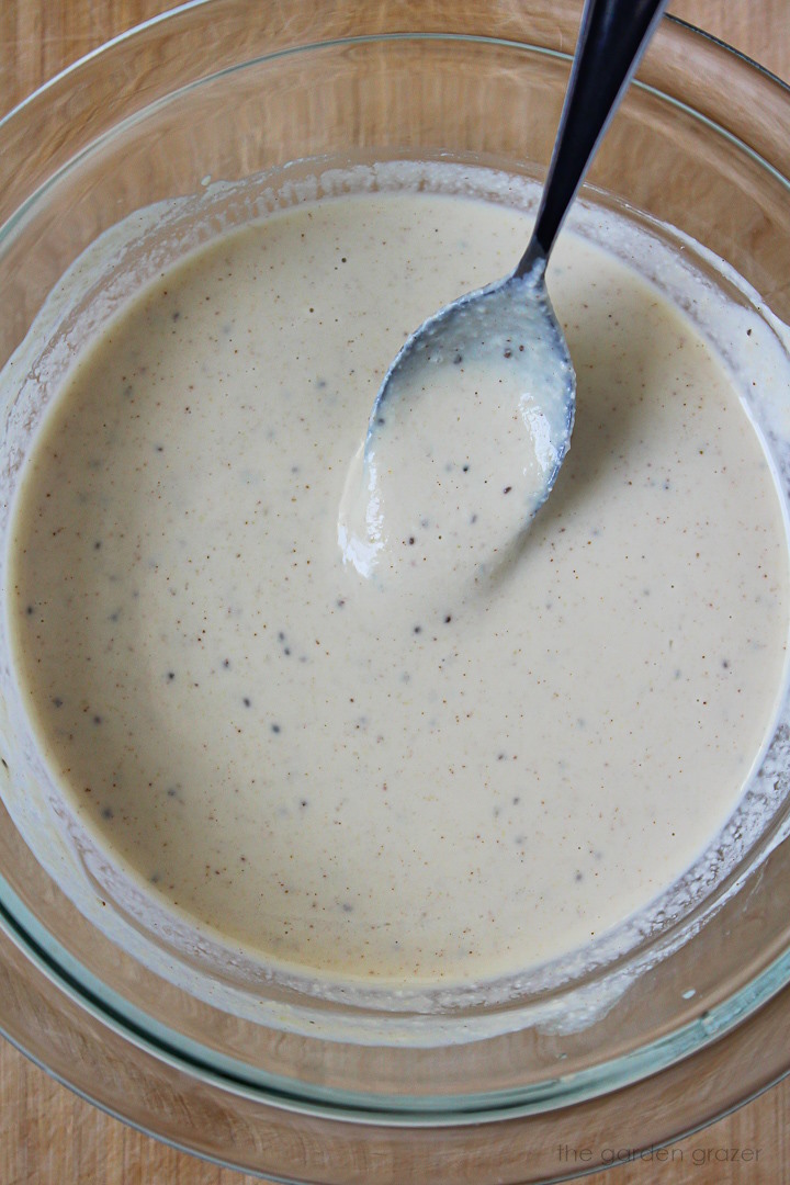 Vegan coleslaw dressing mixed together in a glass bowl with metal spoon