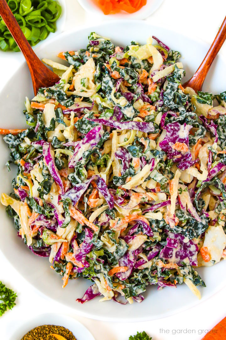 Kale and cabbage slaw in a white bowl tossed with creamy coleslaw dressing