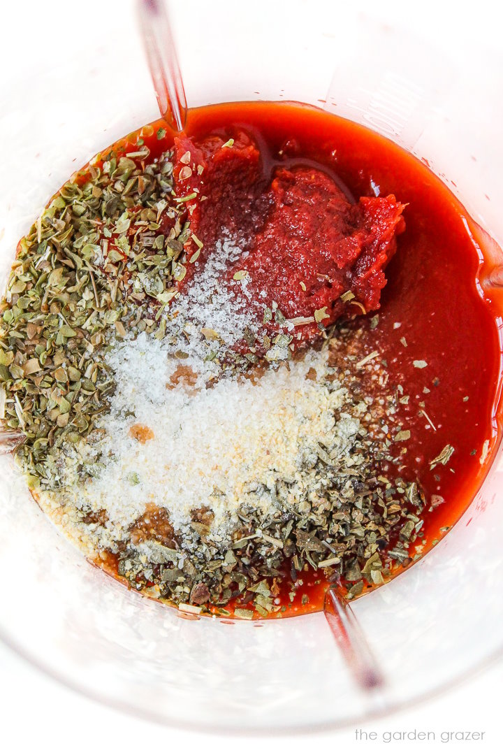 Tomato puree, tomato paste, dried herbs, and seasonings in a small blender jar before blending