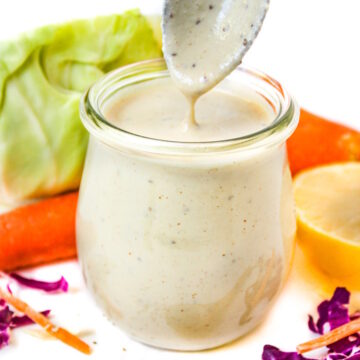 Spoon lifting out vegan coleslaw dressing from a small glass jar