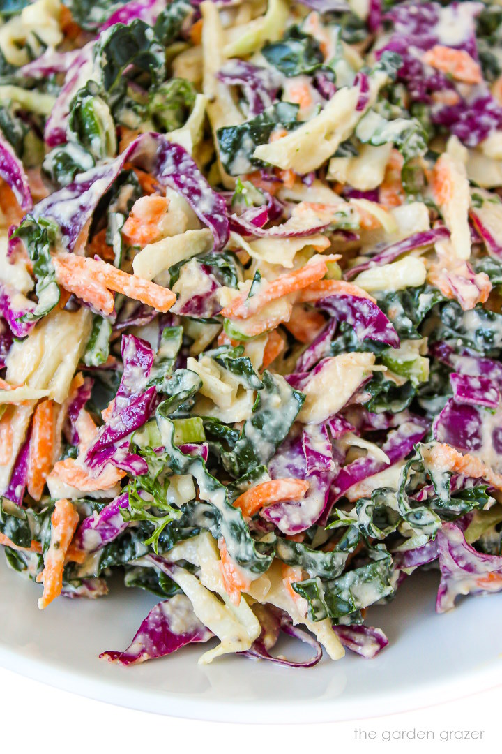 Close up view of vegan kale slaw with creamy dressing on a white plate