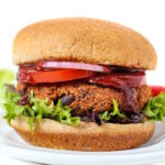 Vegan black bean walnut burger on a bun with lettuce, tomato, onion, and BBQ sauce