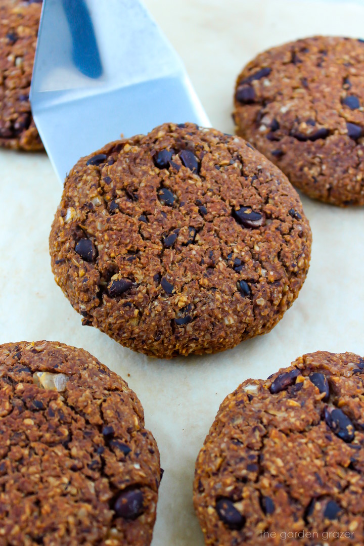 Metal spatula lifting up a black bean walnut burger patty from a baking sheet