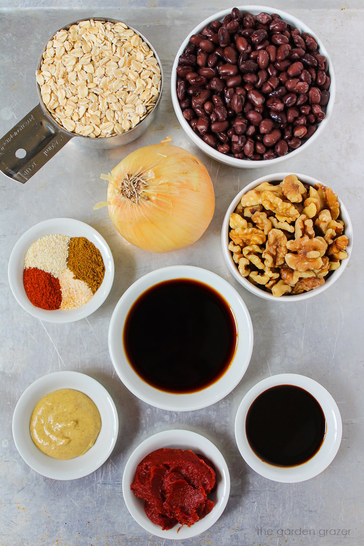 Black beans, nuts, oats, onion, tomato paste, and spice ingredients laid out on a metal tray