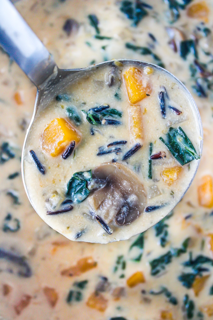 Ladle scooping out creamy soup from a stockpot while cooking