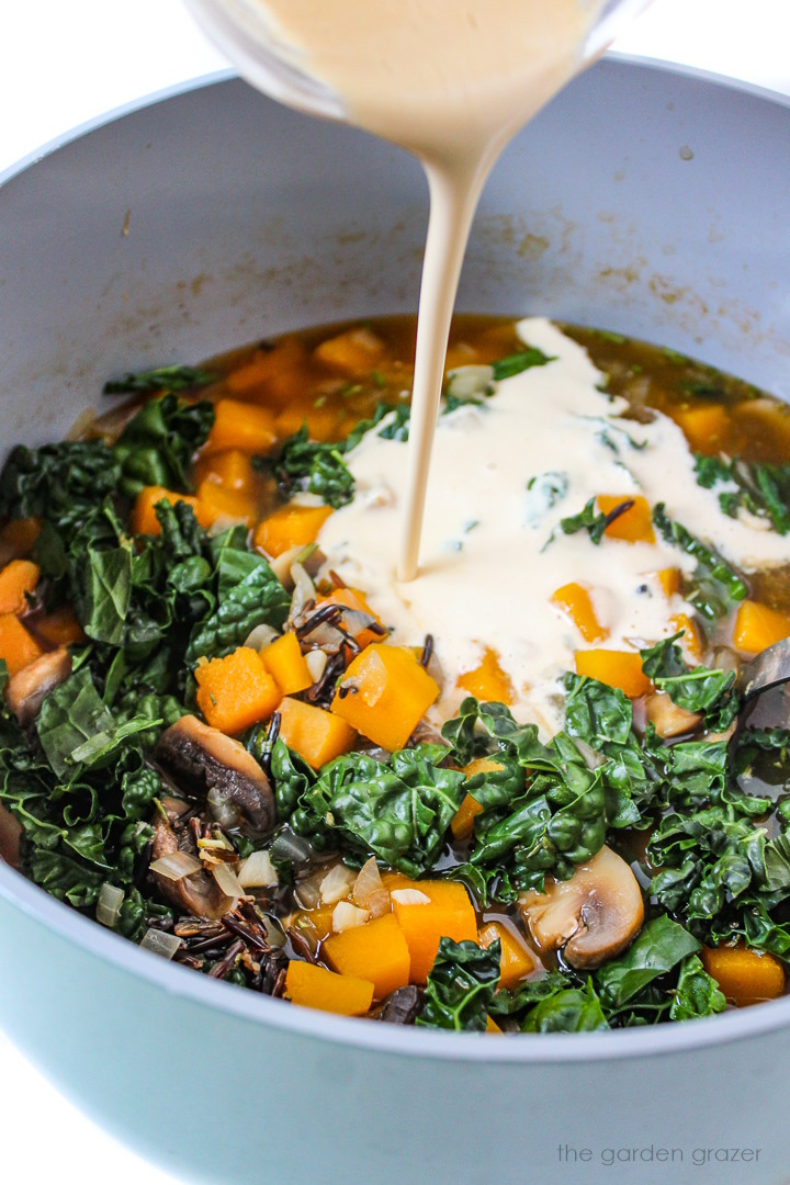 Pouring a cashew cream sauce into soup in a stockpot