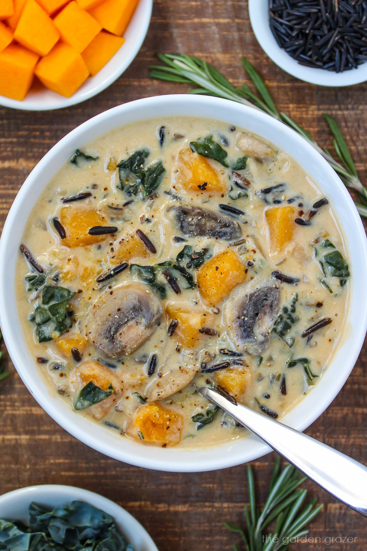 Overhead view of butternut squash wild rice soup in a white bowl with spoon