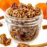 Vegan pumpkin pie spice granola in a small glass jar on a white table