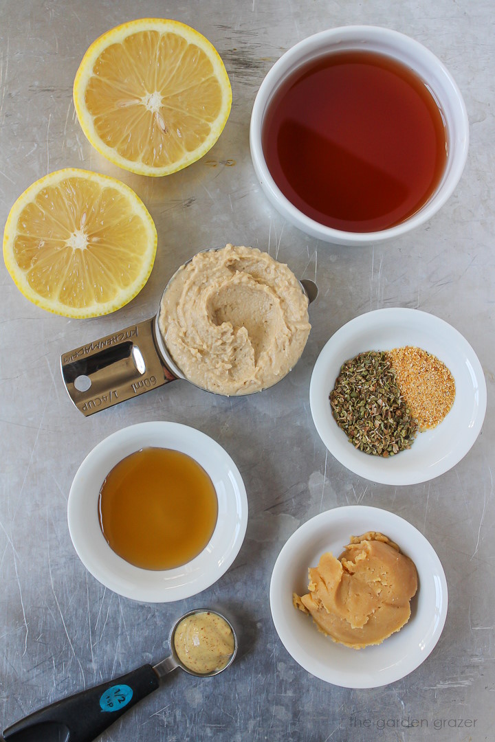 Fresh lemon, hummus, vinegar, miso, and dried herb ingredients laid out on a metal tray