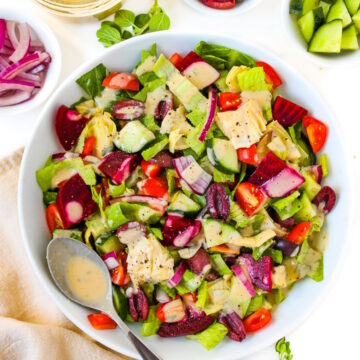 Vegan Greek Salad in a white bowl with homemade dressing on the side