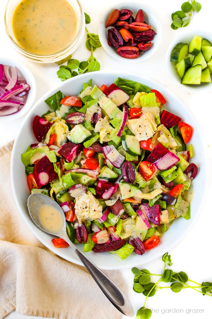 Vegan Greek Salad in a white bowl with homemade dressing on the side