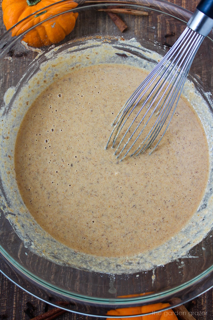 Overhead view of vegan pumpkin waffle batter whisked together in a glass bowl
