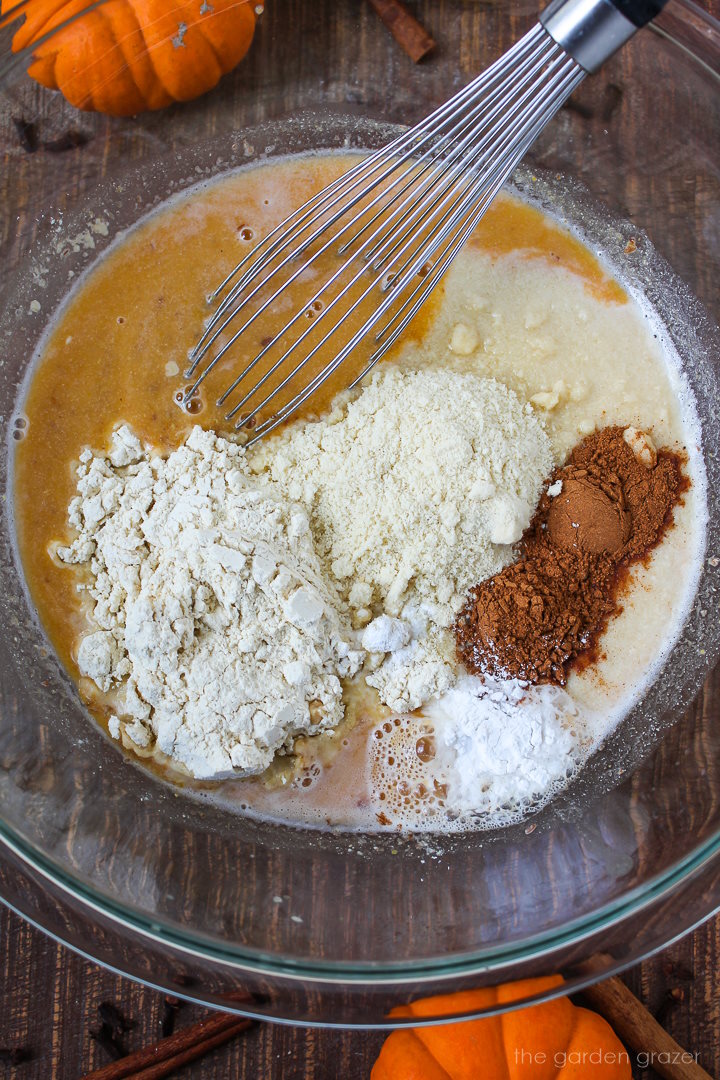 Overhead view of preparing batter ingredients in a large glass bowl before whisking together