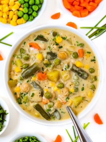 Creamy vegetable chowder in a white bowl with spoon