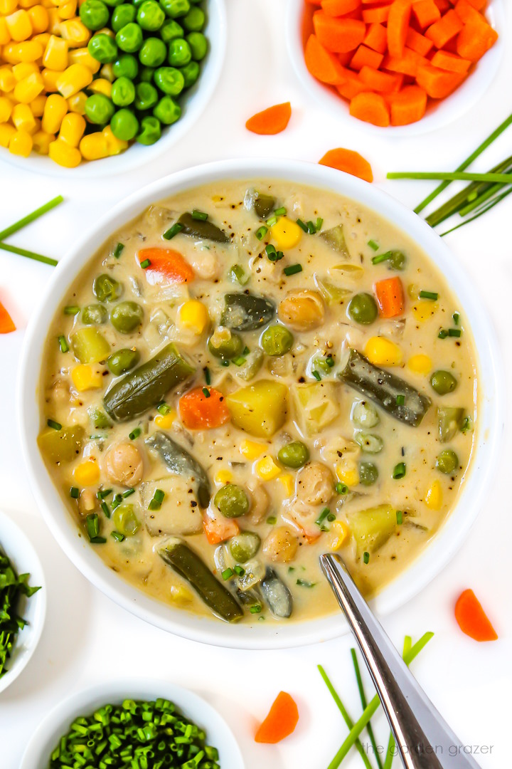 Creamy vegetable chowder in a white bowl with spoon