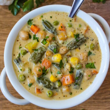 Vegan vegetable chowder in a white soup bowl with serving spoon