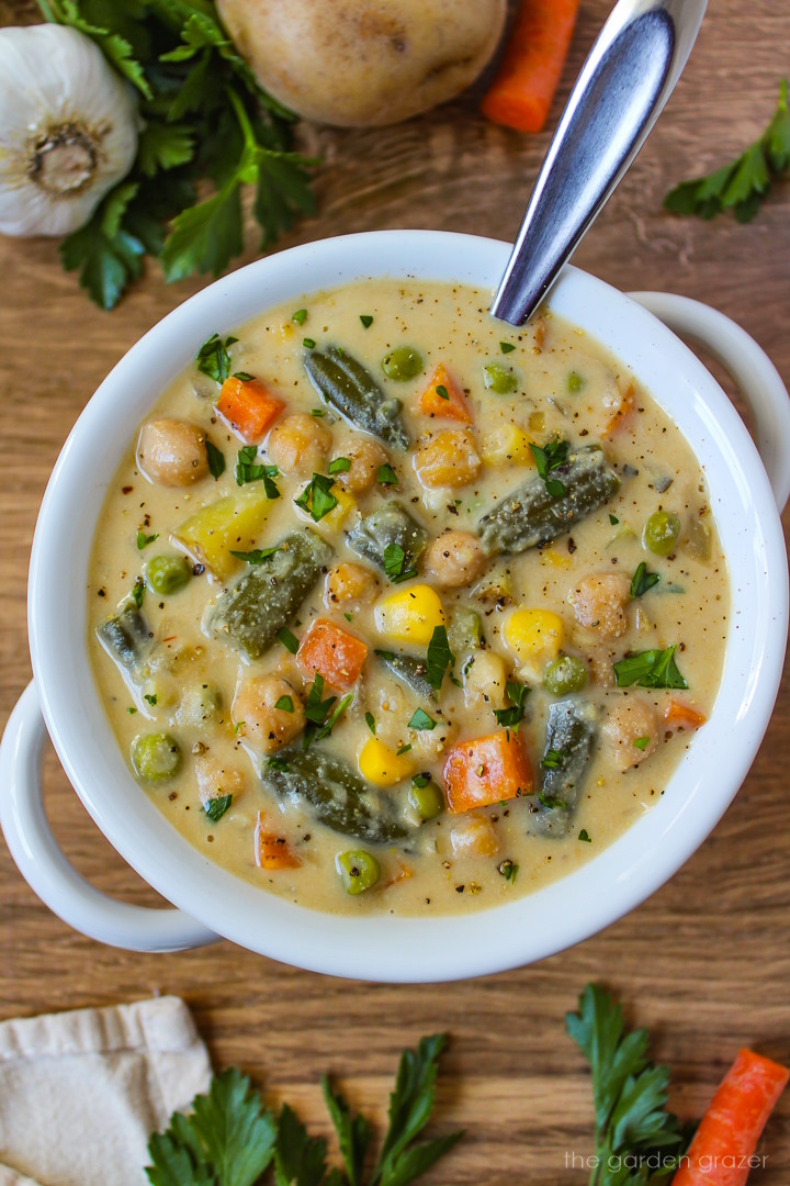 Vegan vegetable chowder in a white soup bowl with serving spoon