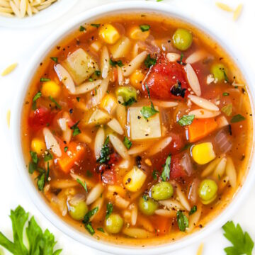 Vegan vegetable orzo soup in a small white bowl with fresh parsley