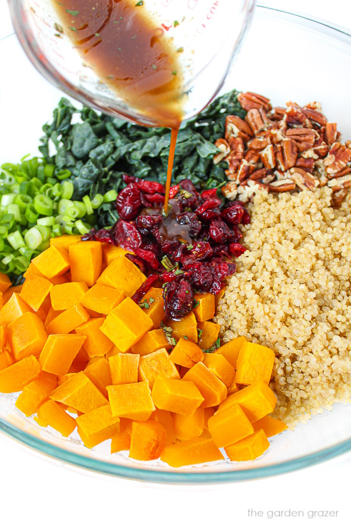 Rosemary maple balsamic dressing being poured over a fall quinoa salad in a large glass bowl