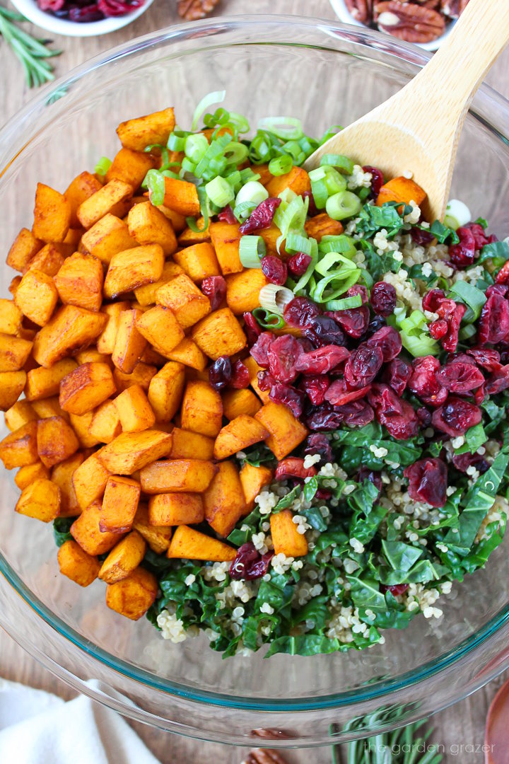 Overhead view of preparing salad ingredients in a large glass bowl before mixing together