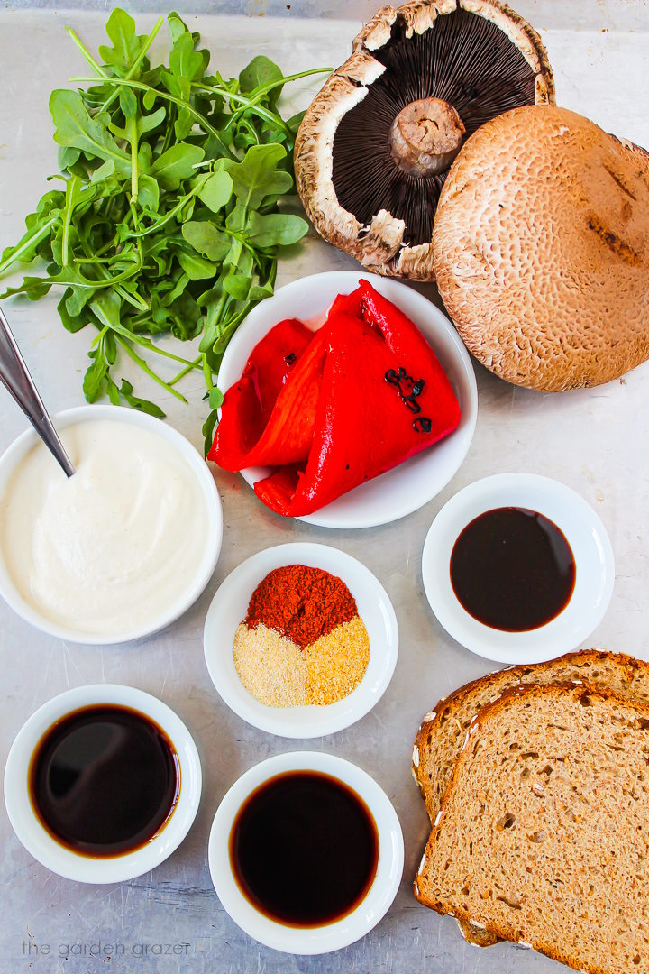 Mushrooms, arugula, garlic aioli, roasted red pepper, bread, and spice ingredients laid out on a metal tray