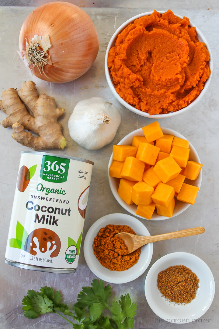 Pumpkin puree, onion, garlic, ginger, coconut milk, butternut squash, and spice ingredients laid out on a metal tray