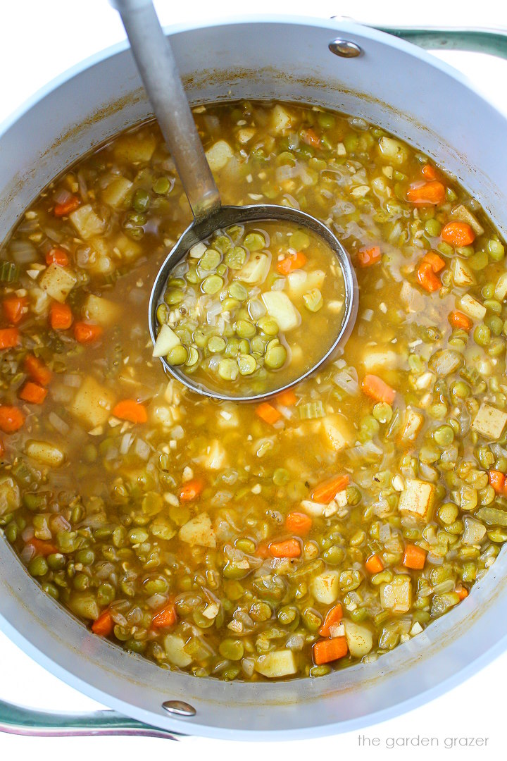 Vegan split pea soup with potato cooking in a large pot before blending together