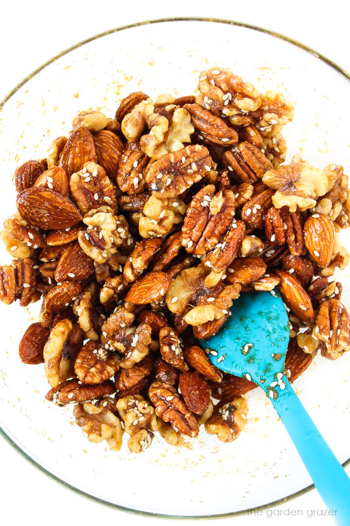 Preparing savory nuts mixture in a glass bowl with spatula before baking