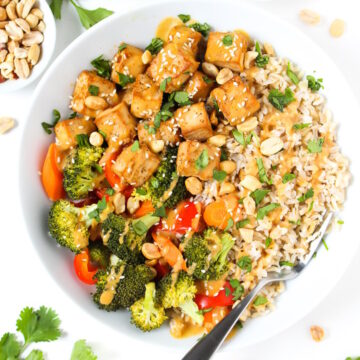 Overhead view of tofu rice bowl with roasted vegetables and topped with peanut sauce