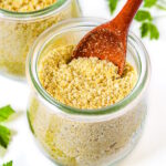 Two small glass jars of vegan parmesan cheese with wooden serving spoons