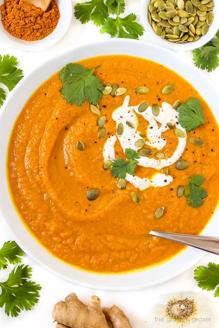 Close-up view of vegan pumpkin curry soup in a white bowl with spoon