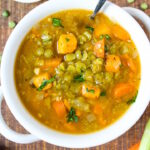 Vegan split pea soup with sweet potato in a white bowl with serving spoon