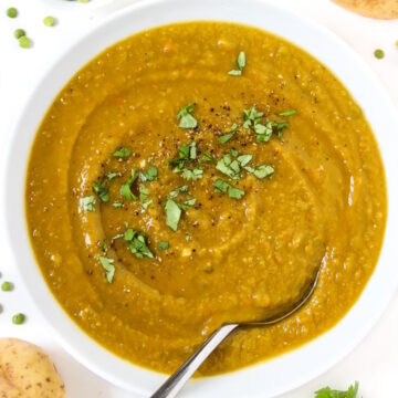 Overhead view of vegan split pea soup in a white bowl with spoon